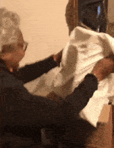 an elderly woman is holding a piece of white cloth in front of a cardboard box that says " fragile " on it