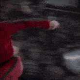 a blurry picture of a person in a white shirt and a red jacket .