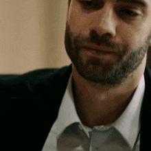 a man with a beard is wearing a white shirt and black jacket
