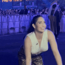 a woman in a white top and gold skirt is dancing in front of a crowd of people .