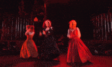 three women are dancing in a dark room with red lights