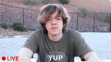 a young man wearing a shirt that says yup is being recorded