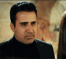 a man in a suit and turtleneck is looking at a woman in a room .