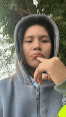 a woman wearing a hooded jacket is making a face