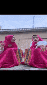 a man and a woman are sitting next to each other in pink dresses