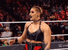 a female wrestler is standing in a wrestling ring with a wwe live sign behind her