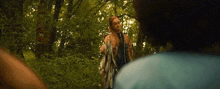 a man and a woman are standing in the woods .