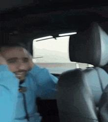 a man in a blue shirt is sitting in a car