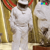 a man in a bee suit is standing in front of a plant
