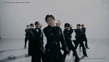 a group of young men are dancing in front of a white wall with gnjb written on the bottom