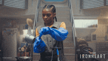 a woman wearing blue gloves is pouring liquid into a container with the words ironheart written on the bottom