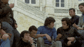 a group of men are sitting on a set of stairs talking