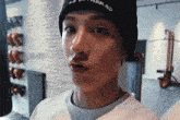 a young man wearing a black beanie and a white shirt is making a funny face in a gym .