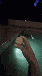 a person holding a small object in their hand in a pool