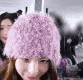 a woman wearing a purple furry hat looks at the camera