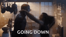 a man and a woman are dancing in a kitchen with the words `` going down '' written on the bottom .