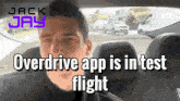 a man sitting in a car with the words overdrive app is in test flight below him