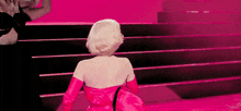 a woman in a pink dress and red gloves is walking down a set of pink stairs