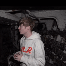 a young man wearing a white hoodie with a red r on it