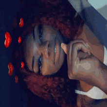 a woman with red hair is laying down with red hearts in her hair