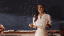 a woman stands in front of a chalkboard with the number 7 written on it