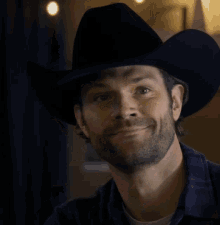 a man wearing a black cowboy hat smiles for the camera