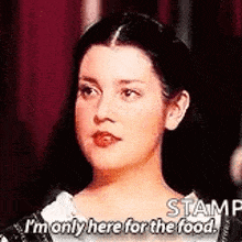 a woman is standing in front of a red curtain and says `` i 'm only here for the food . ''
