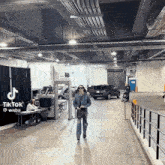 a woman is walking down a hallway in a building with cars parked in the background