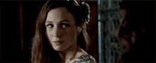 a woman with long hair and a flower in her hair is looking at the camera .