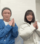 a man wearing a blue cardigan and a woman wearing a white jacket with the word enjoy written on it