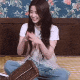 a woman is sitting on a bed with her legs crossed and holding a wicker bag .