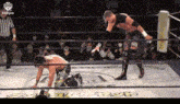 two men are wrestling in a wrestling ring with a referee watching .