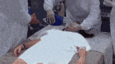 a person in a white gown is laying on a bed with a blue bag on their face