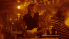 a man is playing a guitar in front of a crowd in a dark room .