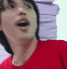 a man in a red t-shirt is making a funny face .