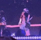 a group of women are dancing on a stage with purple lights