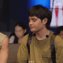 a young man wearing a backpack and a necklace with the letters zky on the bottom