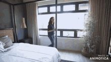 a woman is standing in front of a sliding glass door in a bedroom ..