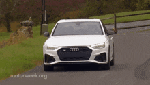 a white audi car is driving down a road