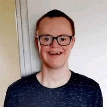 a young man wearing glasses and a blue shirt is smiling .