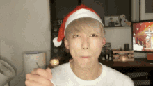 a man wearing a santa hat is holding a spoon in his hand