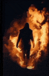 a man in a hooded jacket is walking through a fire