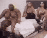 a group of naked women are sitting on a bed in a room .