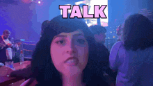 a woman stands in front of a sign that reads talk