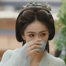 a woman is drinking from a small blue cup