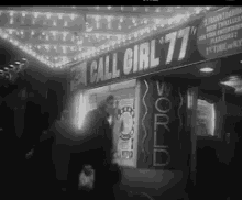 a black and white photo of a call girl 77 sign