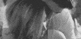 a black and white photo of a man and a woman hugging each other .