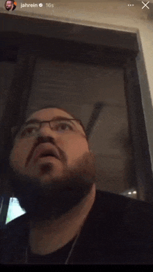 a man with glasses and a beard is looking up at the camera with the name jahrein above him