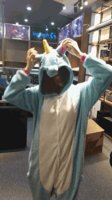 a person wearing a blue unicorn costume in front of a logitech sign