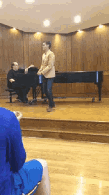 a man sits at a piano while a woman stands in front of it